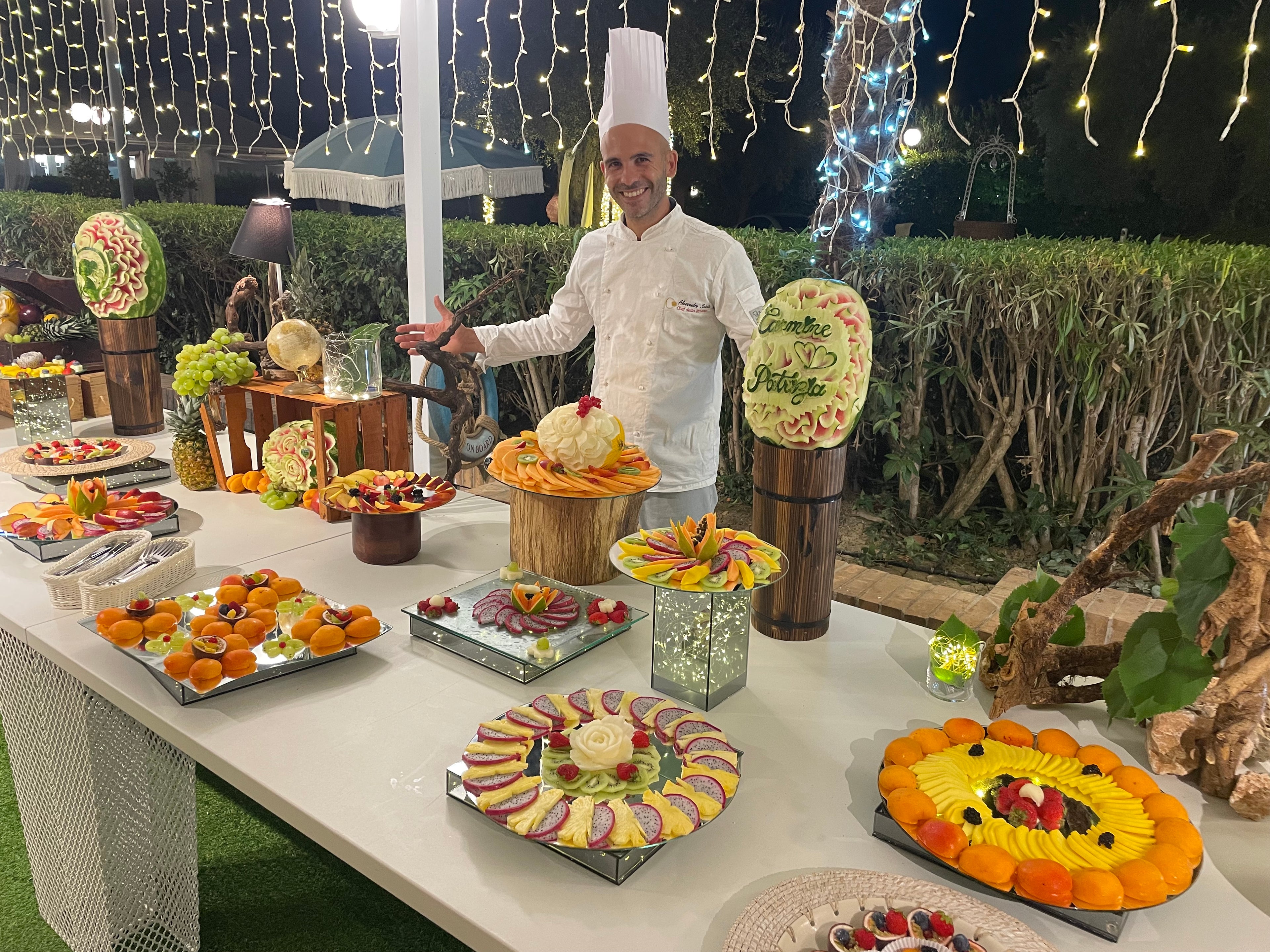 Chef Alessandro Scintu davanti al buffet di frutta scenografico per matrimonio con sculture su anguria