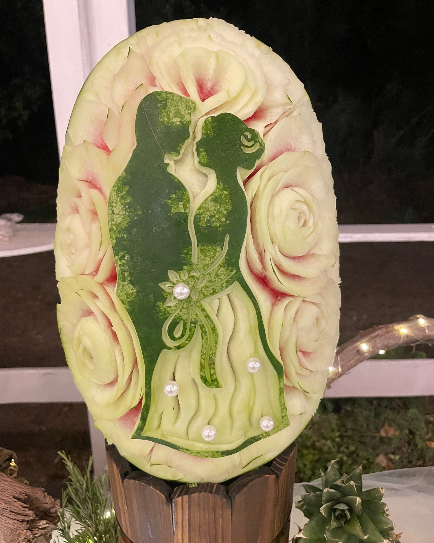Scultura matrimoniale su anguria con silhouette degli sposi tra rose intagliate a mano
